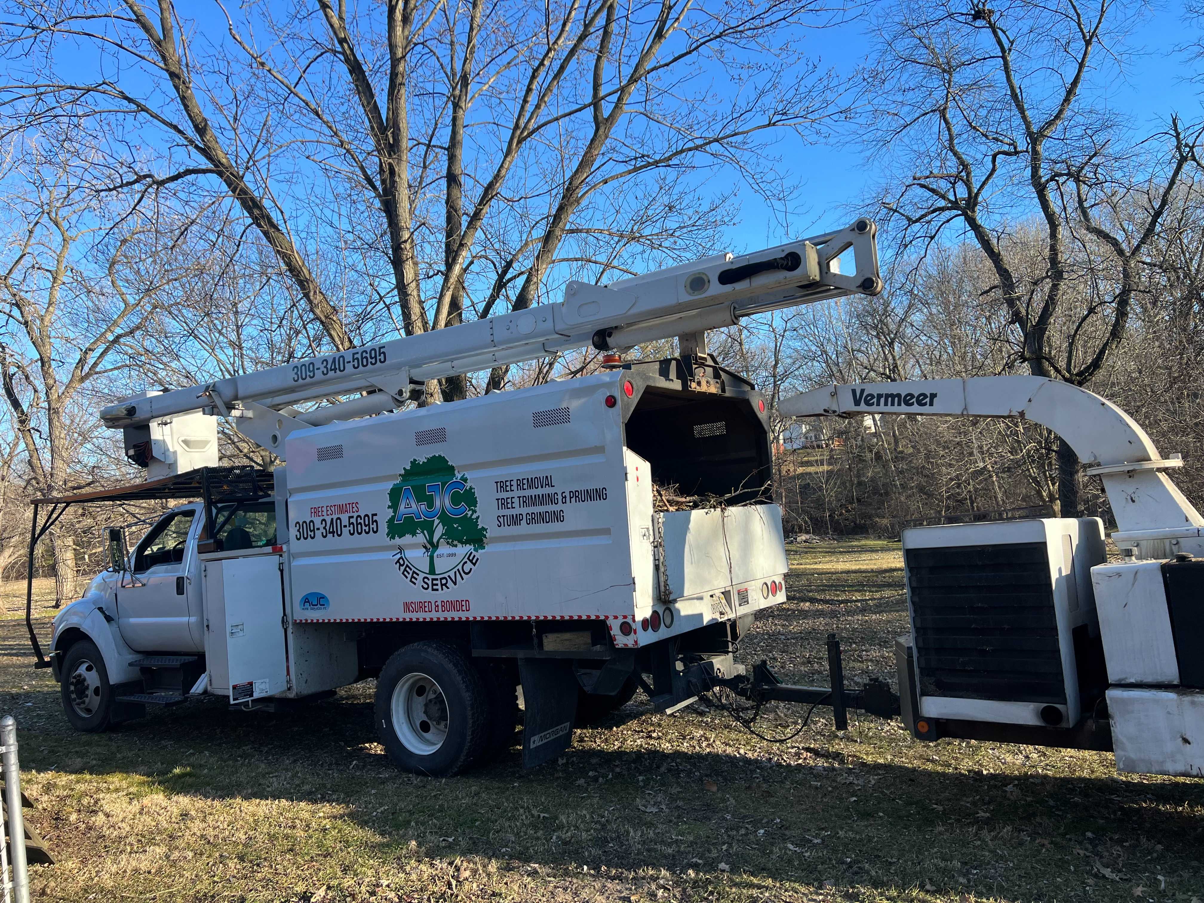AJC Tree Service truck with crane parked in winter landscape