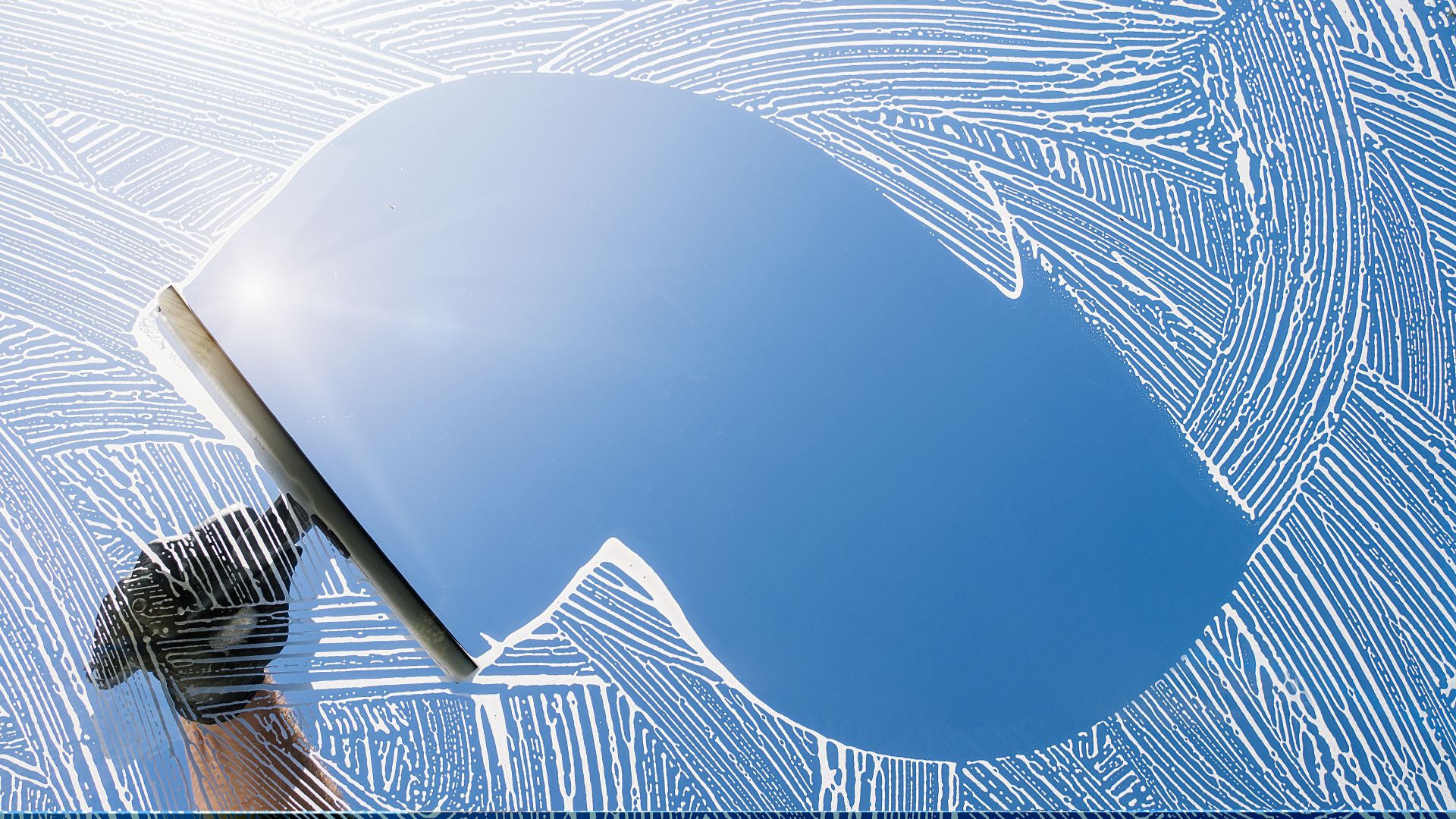 Squeegee cleaning blue window with intricate white fingerprint-like patterns