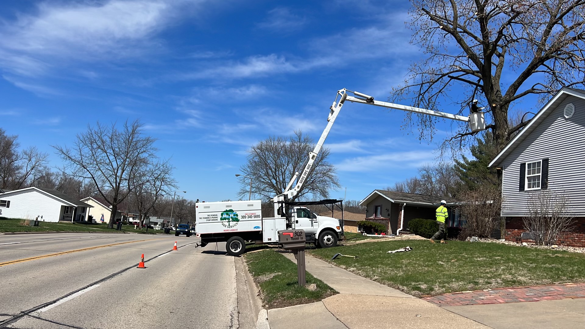 Utility truck with raised bucket near residential street on sunny day