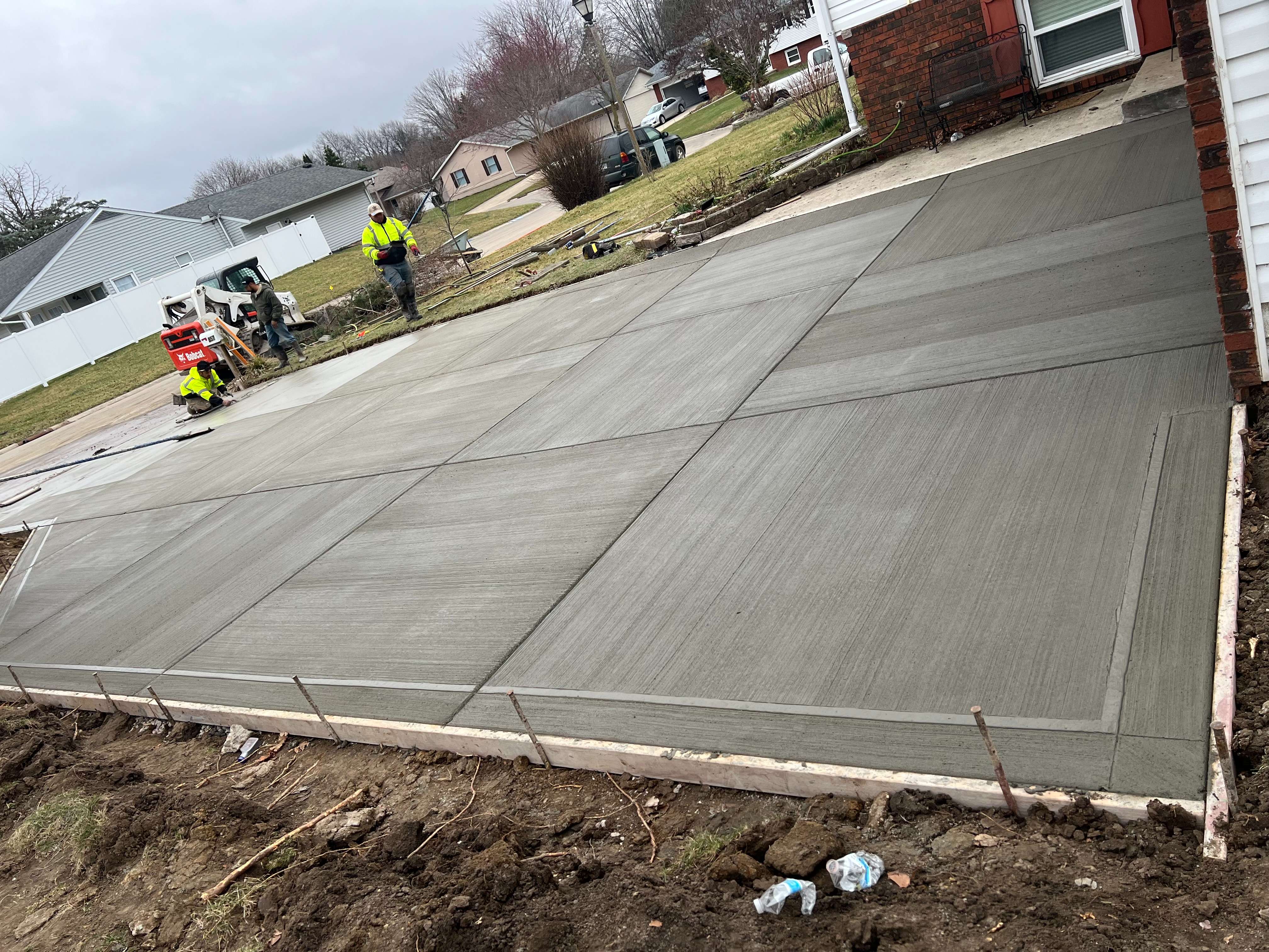 Construction workers finishing a new concrete driveway in suburban neighborhood