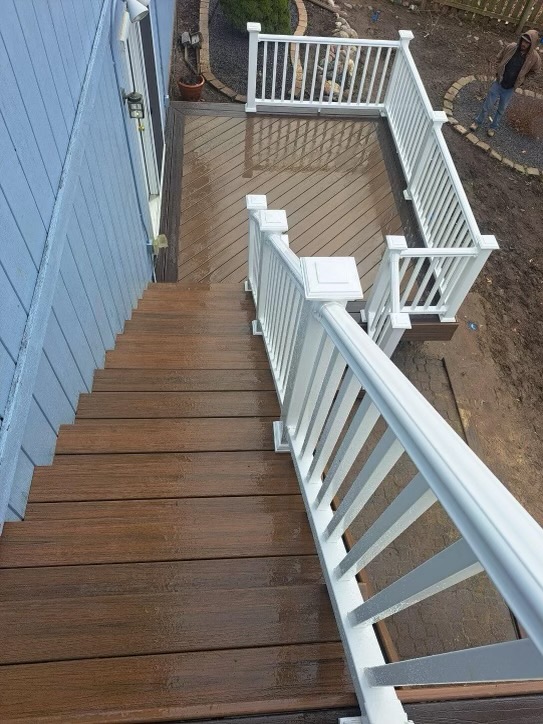 Wooden deck with white railings and stairs leading to backyard