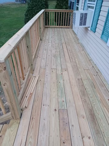 Wooden deck with railing next to blue house and green lawn
