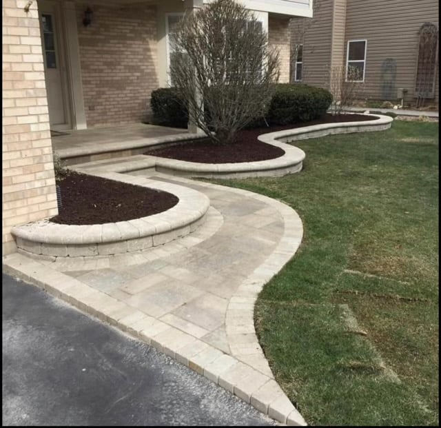 Curved stone walkway and landscaped beds with mulch in suburban front yard